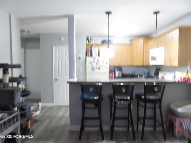 kitchen with decorative light fixtures, kitchen peninsula, white appliances, light brown cabinets, and a breakfast bar area