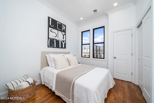 bedroom with a closet, dark hardwood / wood-style flooring, and crown molding