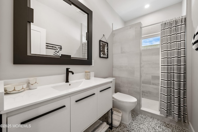 bathroom featuring vanity, toilet, and a tile shower