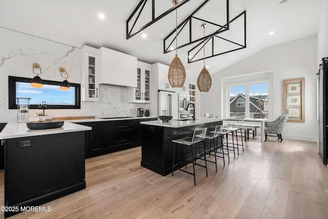 kitchen with white cabinets, a kitchen island with sink, a breakfast bar area, and tasteful backsplash