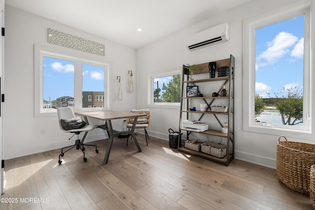 home office with an AC wall unit and light wood-type flooring