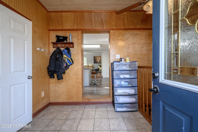 interior space featuring light tile patterned floors, wooden walls, and ceiling fan