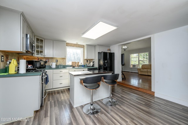 kitchen with white cabinetry, a center island, dark hardwood / wood-style flooring, decorative backsplash, and black appliances