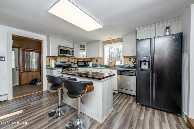 kitchen featuring dark wood-type flooring, black appliances, a skylight, a kitchen island, and white cabinets