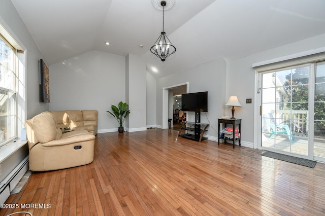 living area featuring vaulted ceiling, a baseboard heating unit, hardwood / wood-style floors, and a notable chandelier