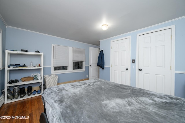 bedroom featuring multiple closets, ornamental molding, and dark hardwood / wood-style floors