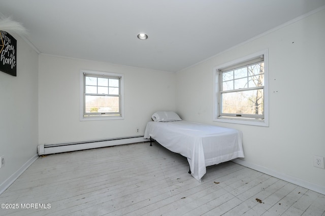 unfurnished bedroom featuring ornamental molding, a baseboard heating unit, and light hardwood / wood-style flooring