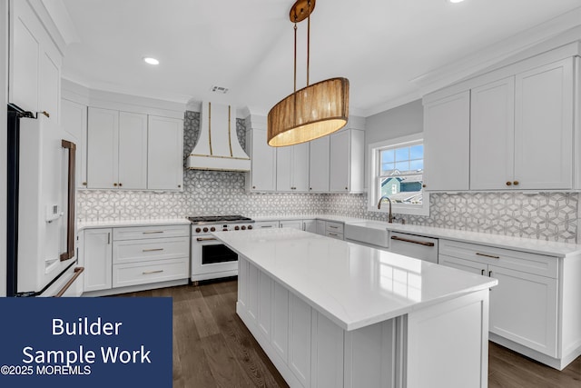 kitchen featuring sink, white appliances, premium range hood, hanging light fixtures, and a center island