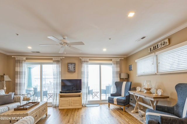 living room with light wood-type flooring, ceiling fan, ornamental molding, and a healthy amount of sunlight