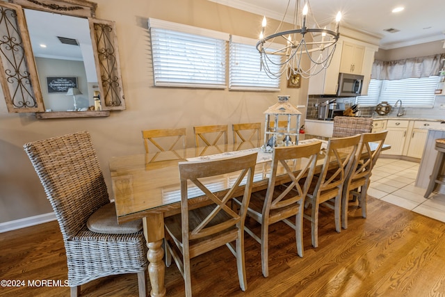 dining area featuring light wood-type flooring, an inviting chandelier, and crown molding