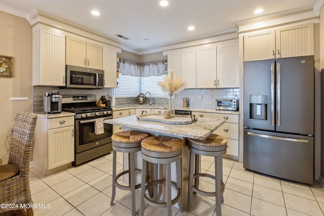 kitchen featuring backsplash, a center island, appliances with stainless steel finishes, light tile patterned floors, and light stone counters