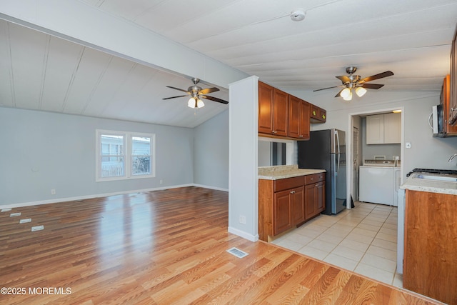 kitchen with ceiling fan, lofted ceiling, appliances with stainless steel finishes, and light hardwood / wood-style flooring