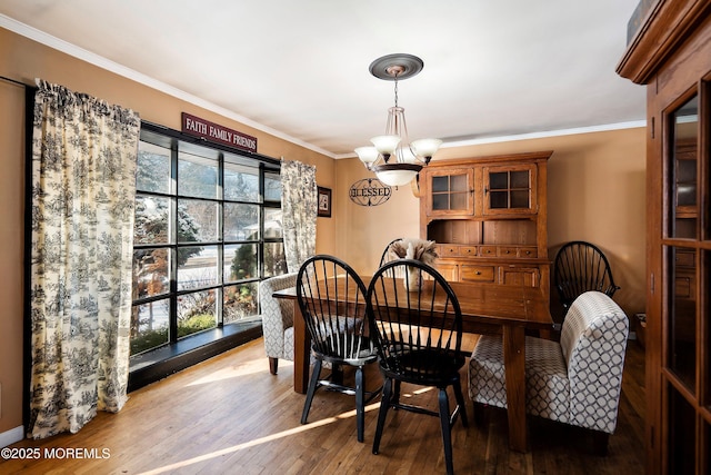 dining room with hardwood / wood-style floors, ornamental molding, and a notable chandelier