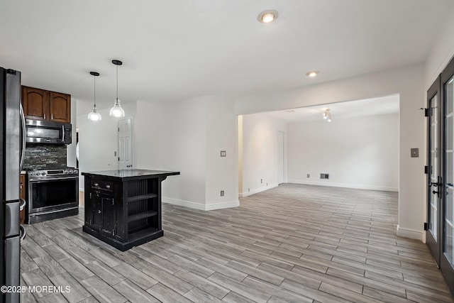 kitchen with dark brown cabinets, pendant lighting, tasteful backsplash, a kitchen island with sink, and stainless steel appliances