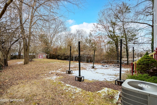 yard layered in snow featuring central air condition unit and a shed