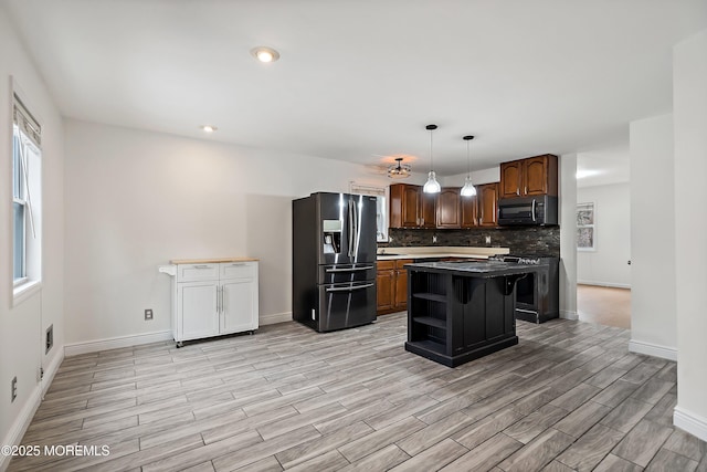 kitchen featuring a center island, stainless steel appliances, a kitchen breakfast bar, backsplash, and hanging light fixtures