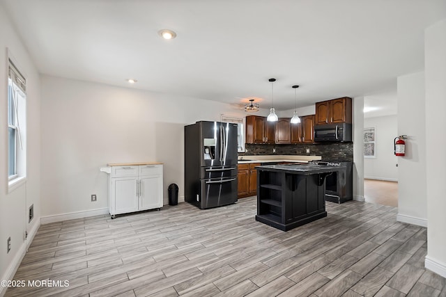 kitchen with a kitchen bar, appliances with stainless steel finishes, tasteful backsplash, hanging light fixtures, and a kitchen island