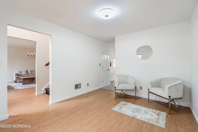 sitting room with hardwood / wood-style floors and a notable chandelier