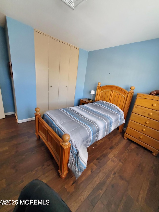 bedroom with dark wood-type flooring and a closet