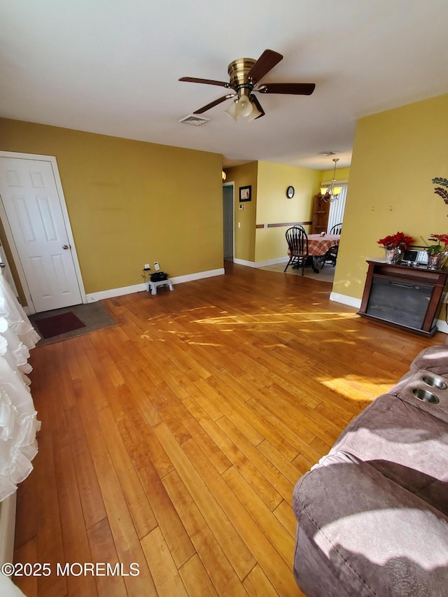 living room with ceiling fan with notable chandelier and hardwood / wood-style floors