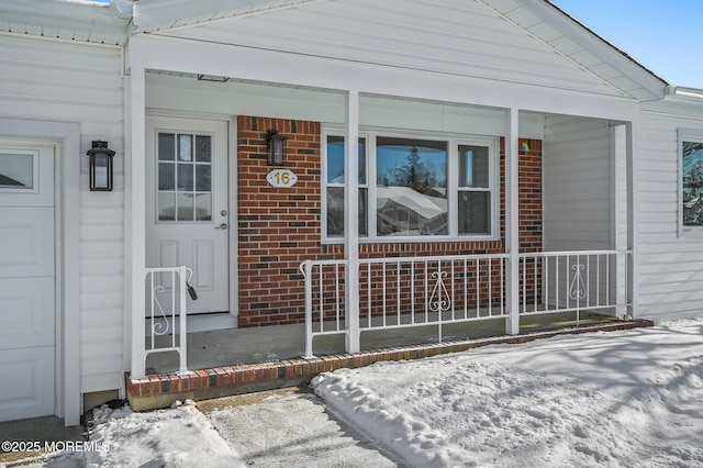 snow covered property entrance with covered porch