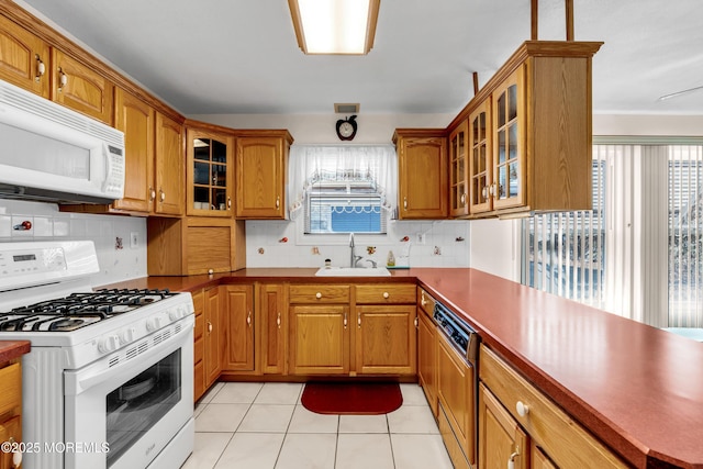 kitchen with tasteful backsplash, white appliances, a healthy amount of sunlight, and sink