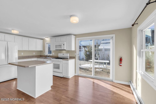 kitchen featuring a wealth of natural light, white appliances, white cabinetry, and a center island