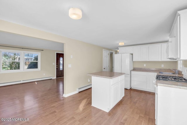 kitchen with white cabinetry, baseboard heating, white fridge, and a kitchen island