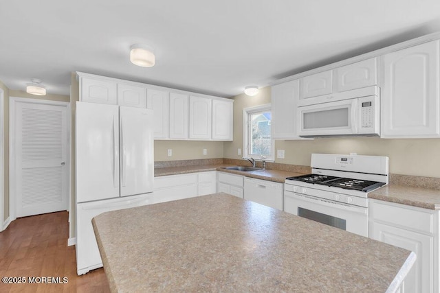 kitchen with white cabinetry, sink, and white appliances