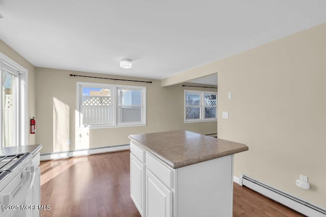 kitchen with baseboard heating, white cabinetry, a wealth of natural light, and a kitchen island