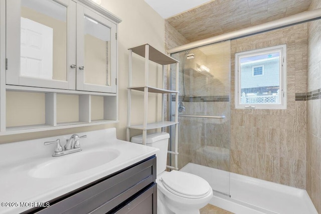 bathroom featuring toilet, a shower with door, and vanity