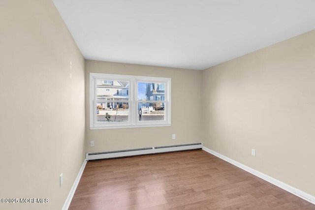 unfurnished room with a baseboard heating unit and light hardwood / wood-style floors