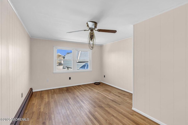 spare room with baseboard heating, crown molding, and light hardwood / wood-style flooring