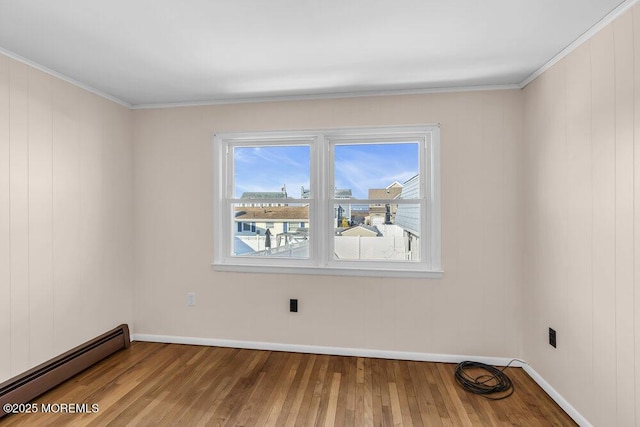 empty room featuring baseboard heating, crown molding, and wood-type flooring