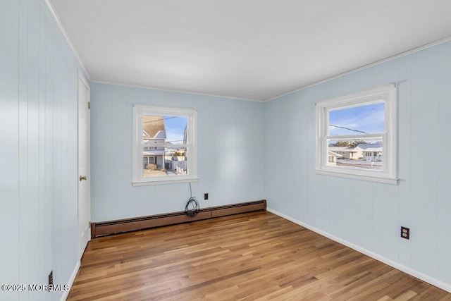 unfurnished room featuring baseboard heating, light hardwood / wood-style flooring, and crown molding