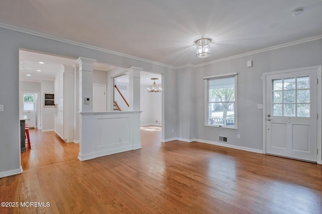 interior space with visible vents, baseboards, ornamental molding, light wood-type flooring, and decorative columns