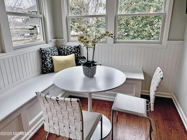 dining space featuring breakfast area, wainscoting, and dark wood finished floors