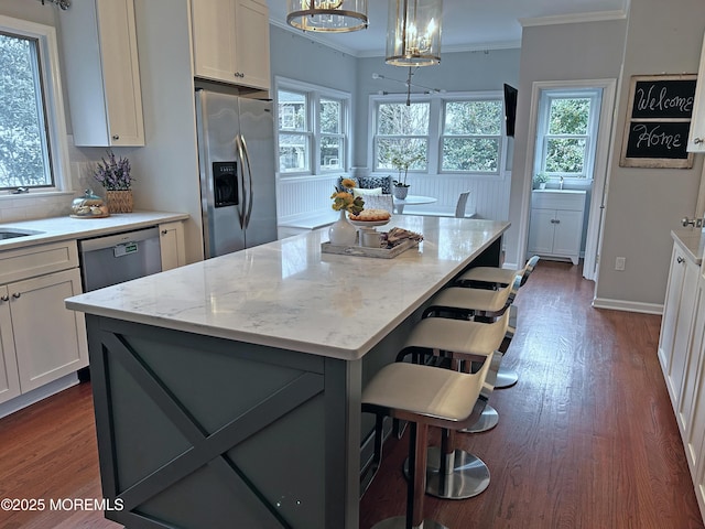 kitchen featuring stainless steel appliances, light stone counters, dark wood-type flooring, and crown molding