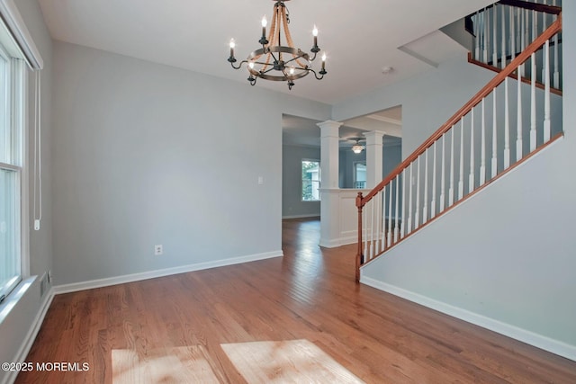 interior space with wood finished floors, baseboards, ornate columns, and stairs