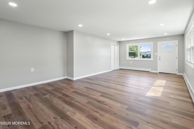 interior space with a baseboard heating unit and wood-type flooring