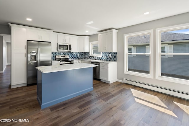 kitchen featuring a baseboard heating unit, a center island, light stone countertops, stainless steel appliances, and white cabinets