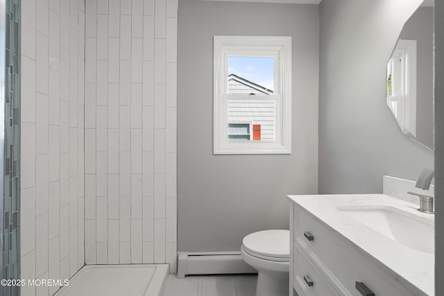 bathroom with toilet, a tile shower, vanity, and a baseboard radiator