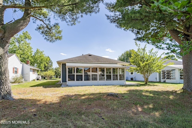 rear view of house with a sunroom and a lawn