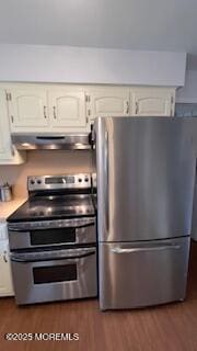 kitchen with white cabinets, appliances with stainless steel finishes, and dark hardwood / wood-style flooring