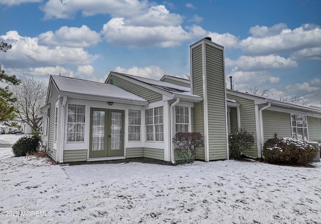 snow covered house featuring french doors