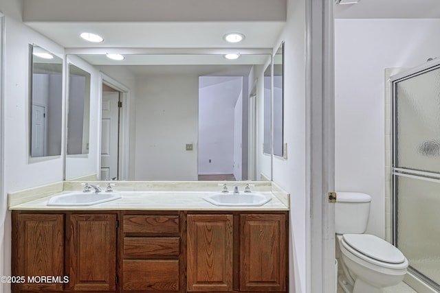 bathroom with vanity, toilet, and a shower with door