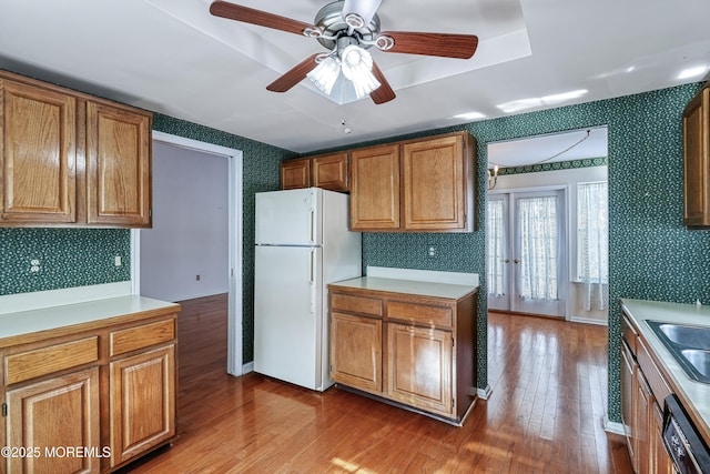 kitchen with sink, light wood-type flooring, white refrigerator, dishwashing machine, and ceiling fan