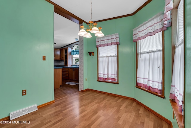 unfurnished dining area featuring a notable chandelier, ornamental molding, and light hardwood / wood-style floors