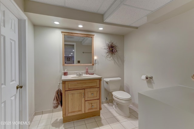 bathroom with a paneled ceiling, toilet, tile patterned floors, and vanity