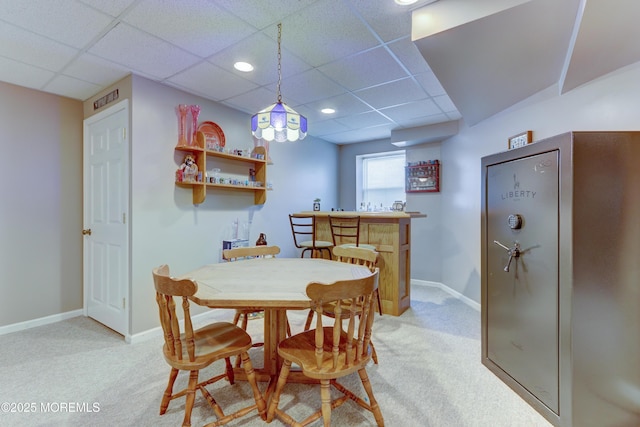 carpeted dining space featuring a drop ceiling and bar area